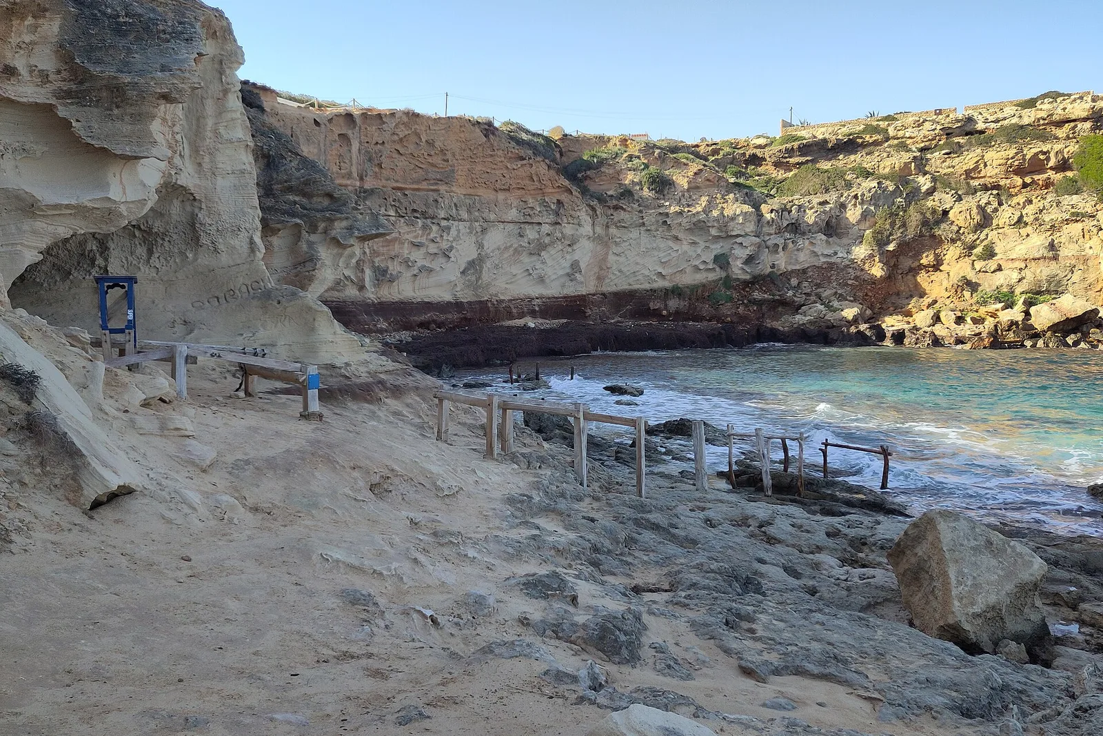 Los varaderos de madera de Cala en Baster, encajados entre paredes de arenisca excavada, con el mar entrando en la cala.