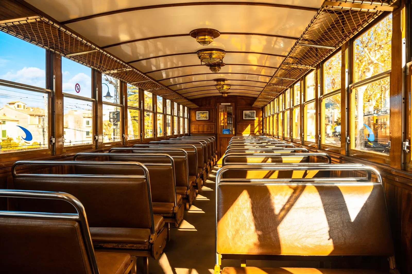 Interior de un vagón del tren de Sóller: bancos de listones de madera, herrajes de latón y luz entrando por las ventanas.