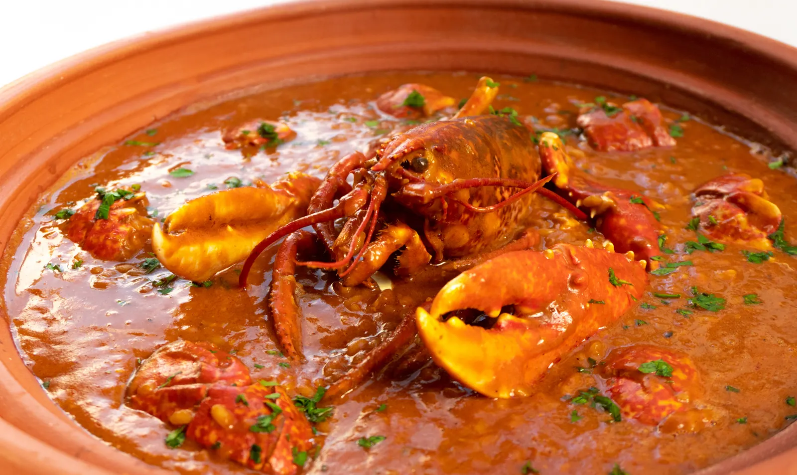 Caldereta de langosta servida en cazuela de barro, el plato marinero emblema de Menorca.