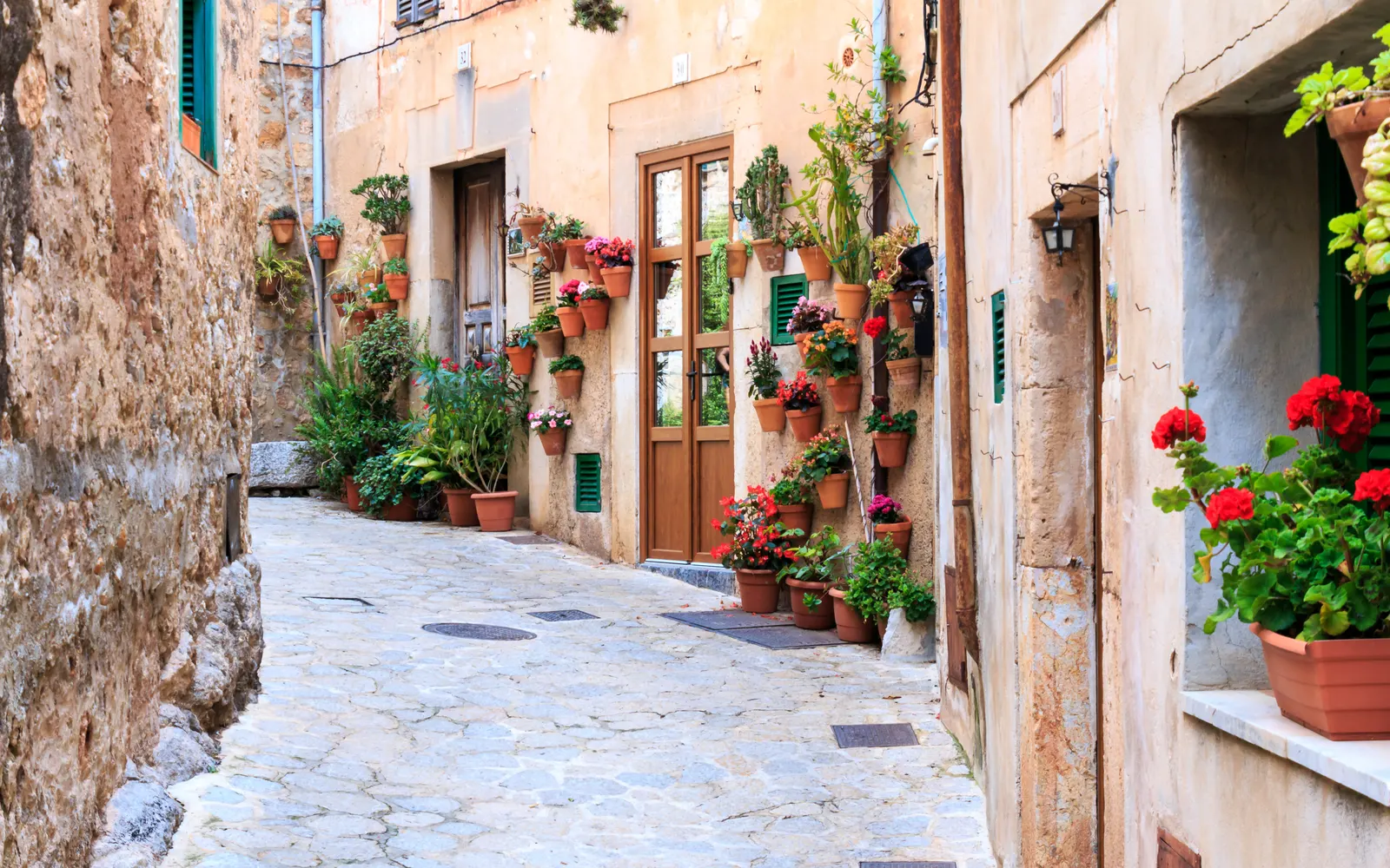 Calle empedrada de Valldemossa, con macetas de geranios colgadas en las fachadas de piedra.