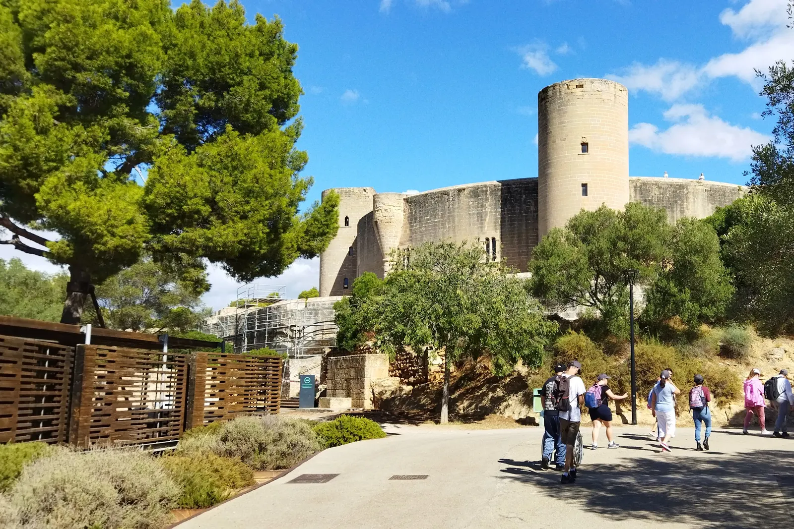 Il castello di Bellver tra i pini, con la sua torre rotonda e visitatori sulla spianata