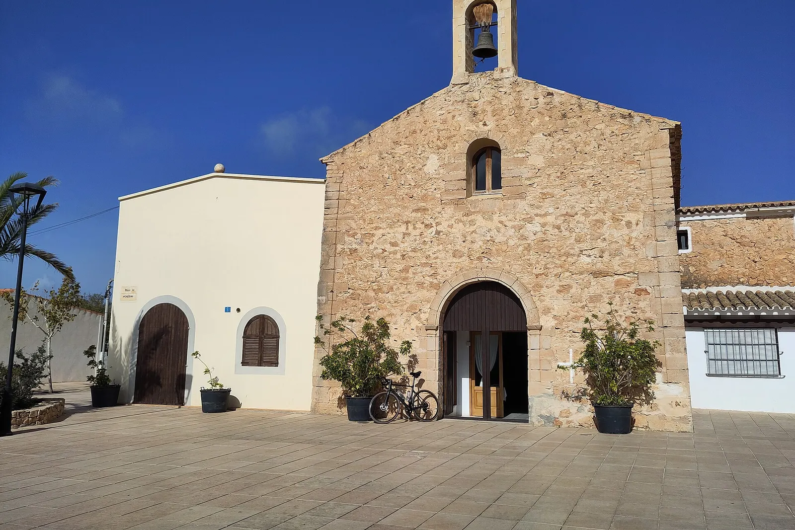 La iglesia de piedra de Sant Ferran de ses Roques, con su espadaña y la plaza delante