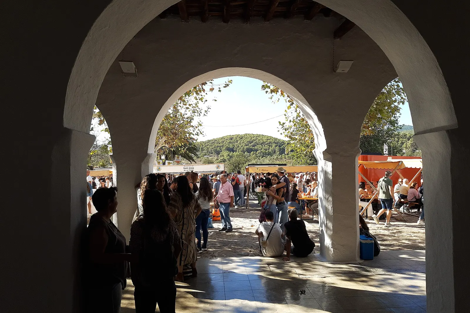 Vecinos saliendo bajo los arcos del porche de la iglesia de Sant Carles de Peralta hacia la fiesta