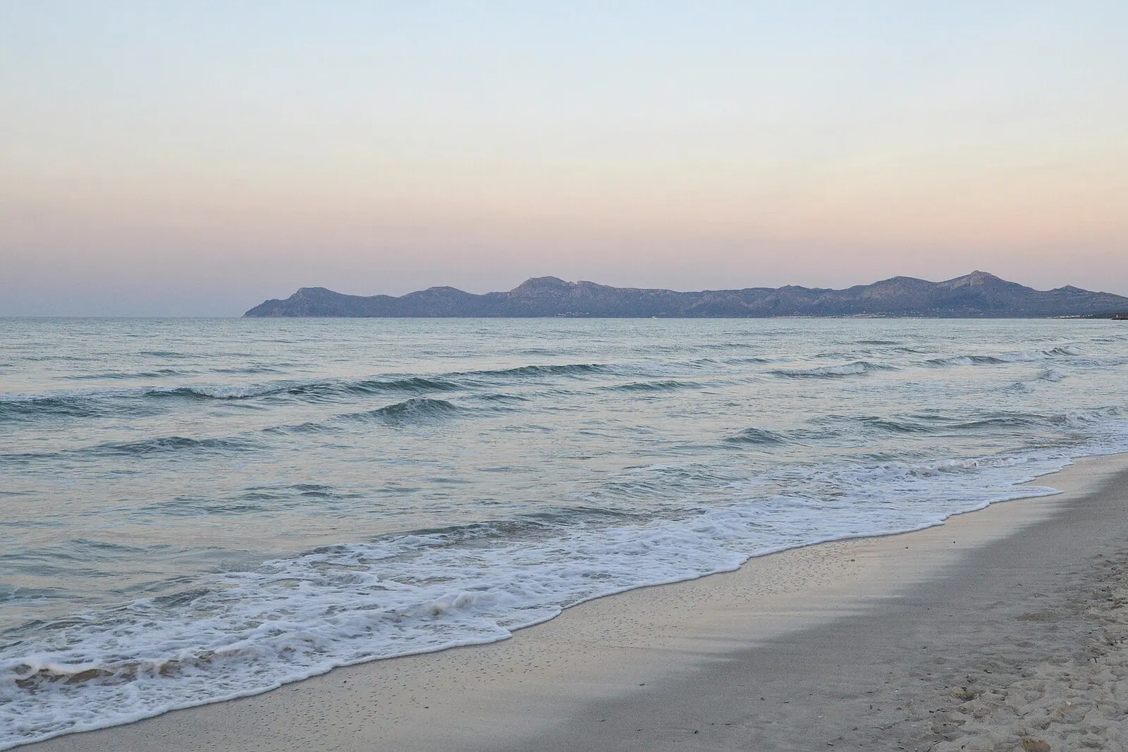 La spiaggia di Muro all'alba, con la baia di Alcúdia calma e le montagne sullo sfondo
