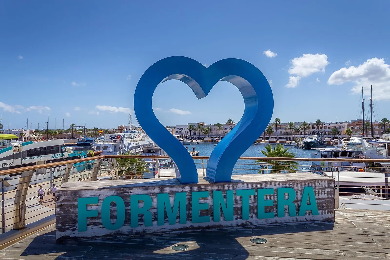 El rótulo de Formentera con forma de corazón en el puerto de La Savina, con los barcos amarrados detrás