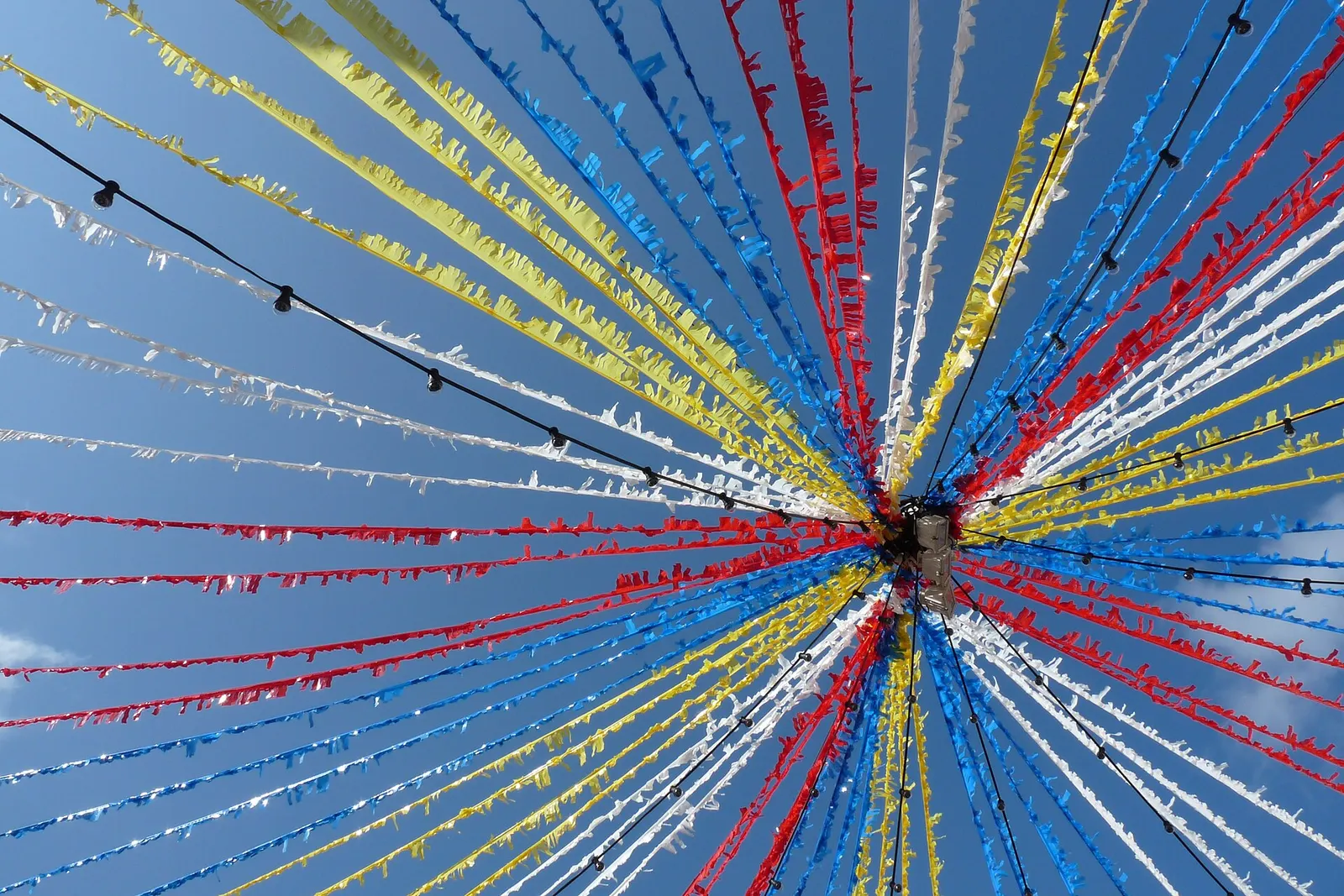Festoni colorati da festa che attraversano una strada di Es Mercadal contro il cielo azzurro