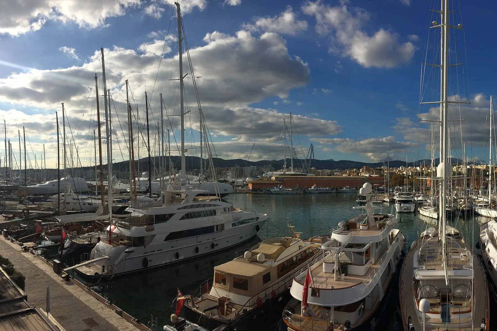 Yates de gran eslora amarrados en el Moll Vell de Palma, bajo un cielo azul con nubes