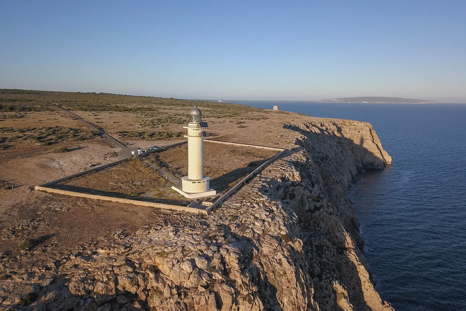 El faro de Cap de Barbaria sobre la meseta llana que acaba en acantilado