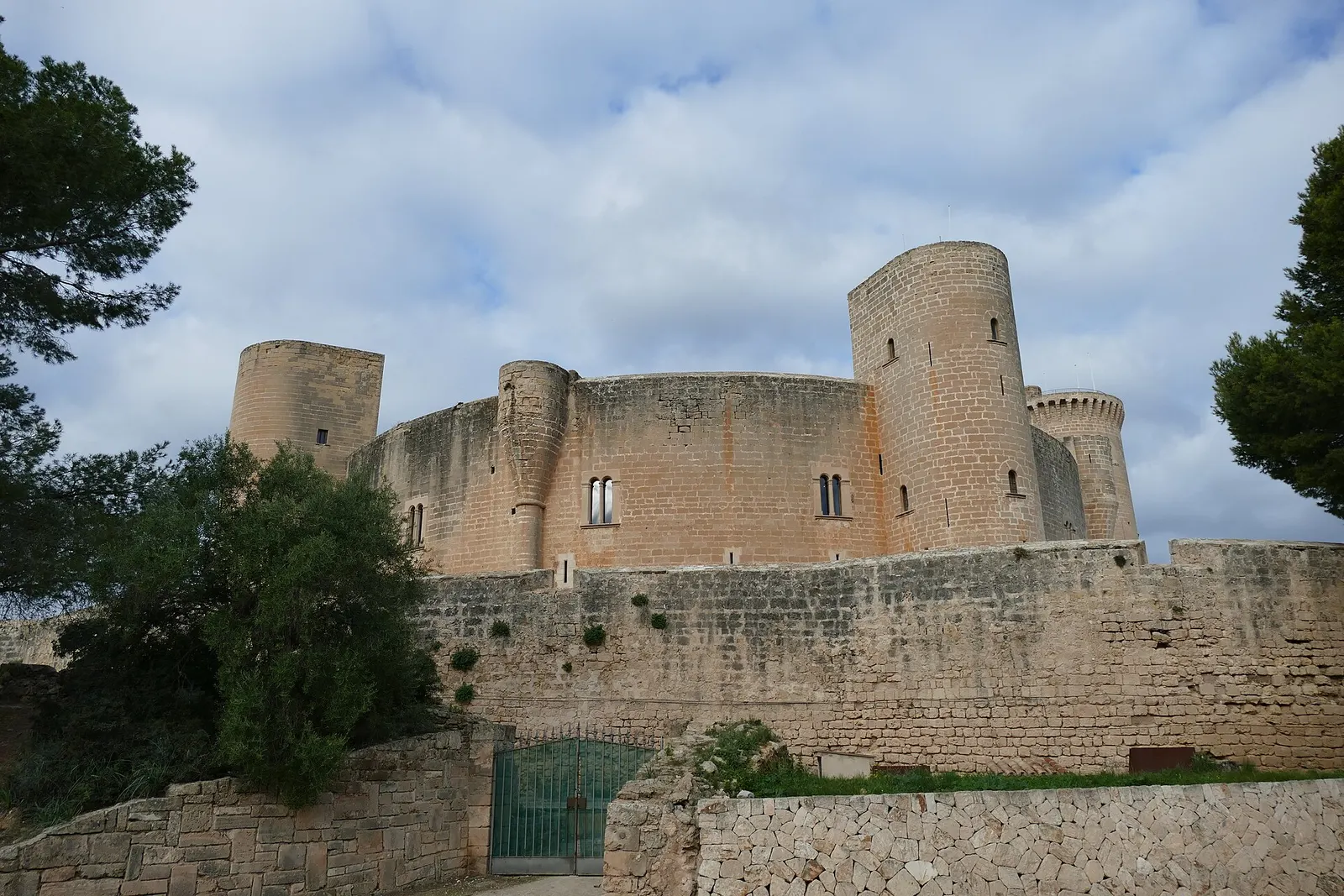 Las murallas y la torre del castillo de Bellver, de planta circular, entre los pinos del bosque