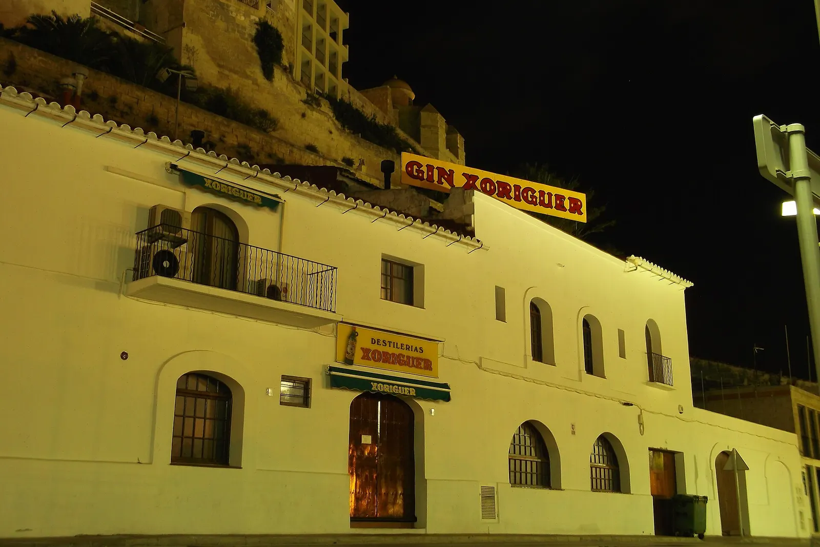 La facciata della distilleria Xoriguer nel porto di Maó, illuminata di notte con la sua insegna