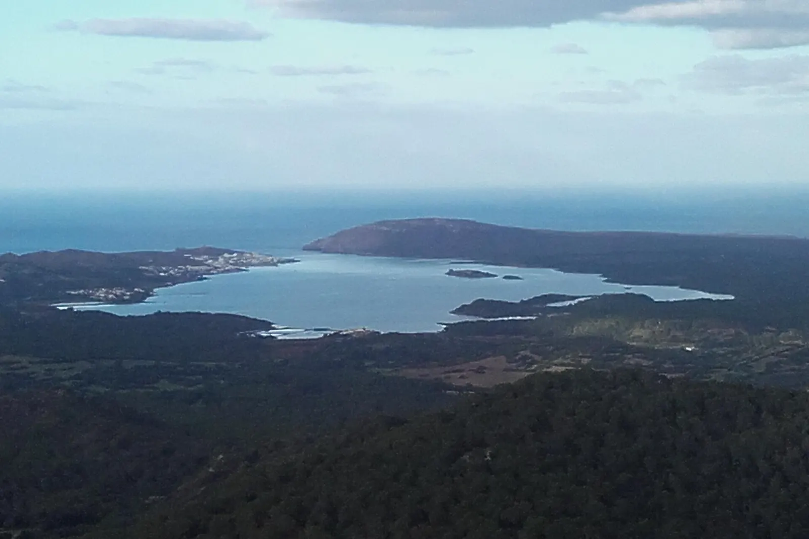 La baia di Fornells vista dall'alto, con l'imboccatura aperta sul mare e la costa nord di Minorca