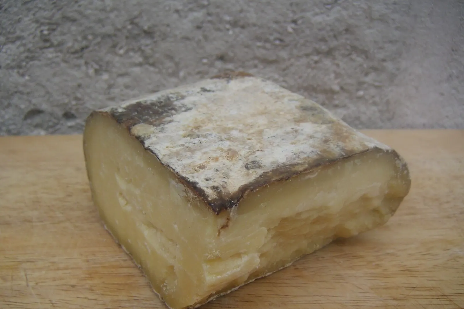 Uno spicchio di formaggio Mahón-Menorca stagionato artigianale, con la crosta grigia e la pasta gialla