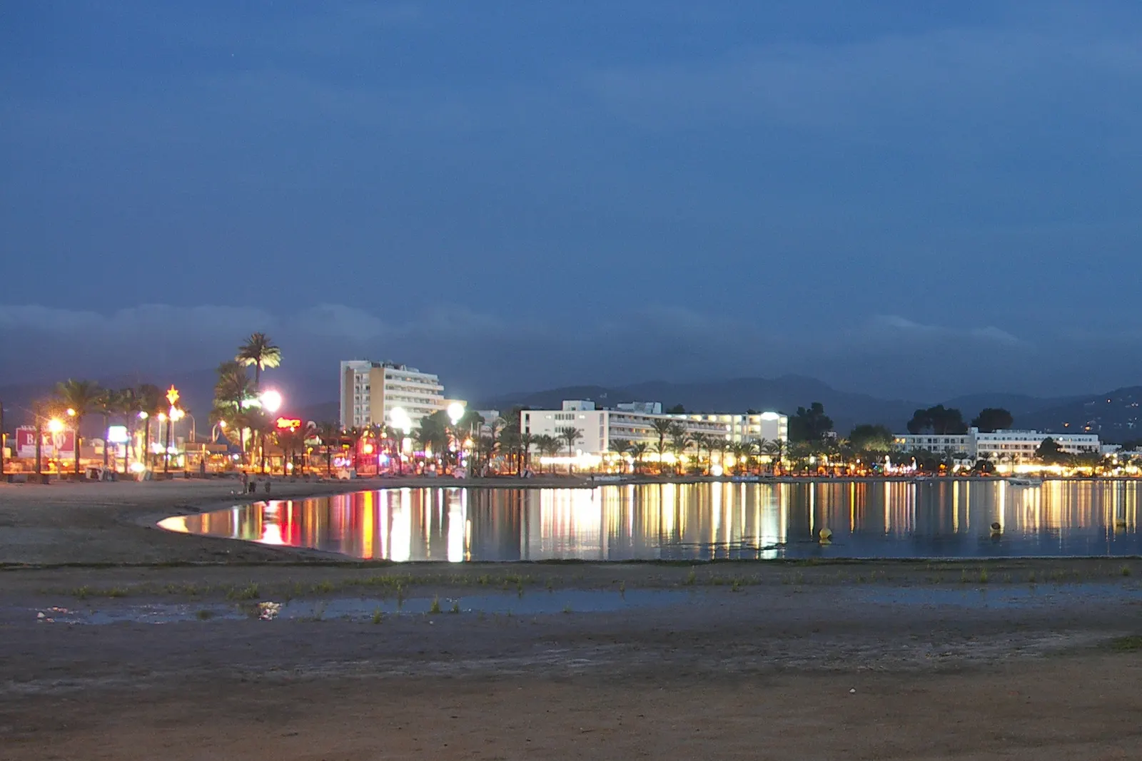 La bahía de Sant Antoni de Portmany al anochecer, con las luces del paseo reflejadas en el agua