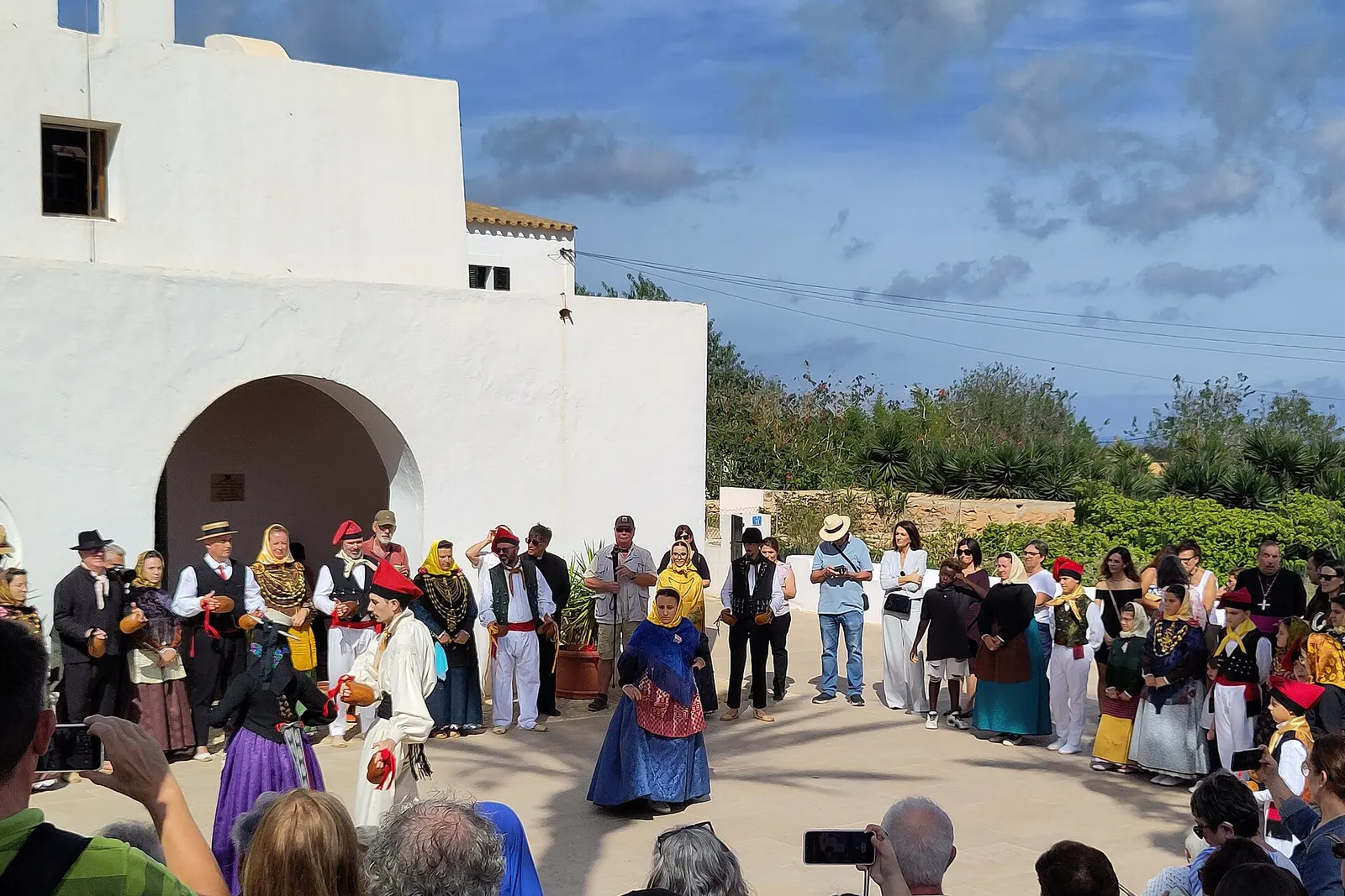 Ball pagès en las fiestas del Pilar: bailadores con traje tradicional ante la iglesia blanca de El Pilar de la Mola