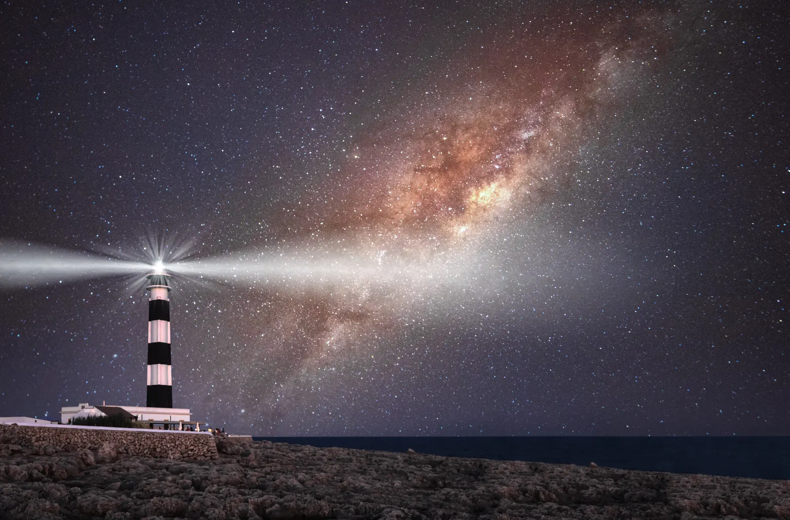 El faro de Cap d'Artrutx, a rayas blancas y negras, bajo la Vía Láctea en una noche de Menorca.