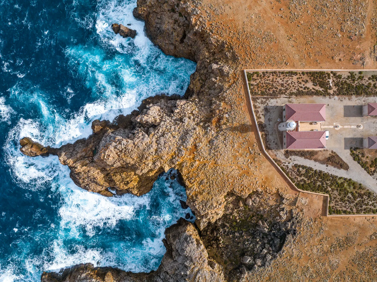 El faro de Punta Nati y la casa de los torreros al borde del acantilado, vistos desde el aire.