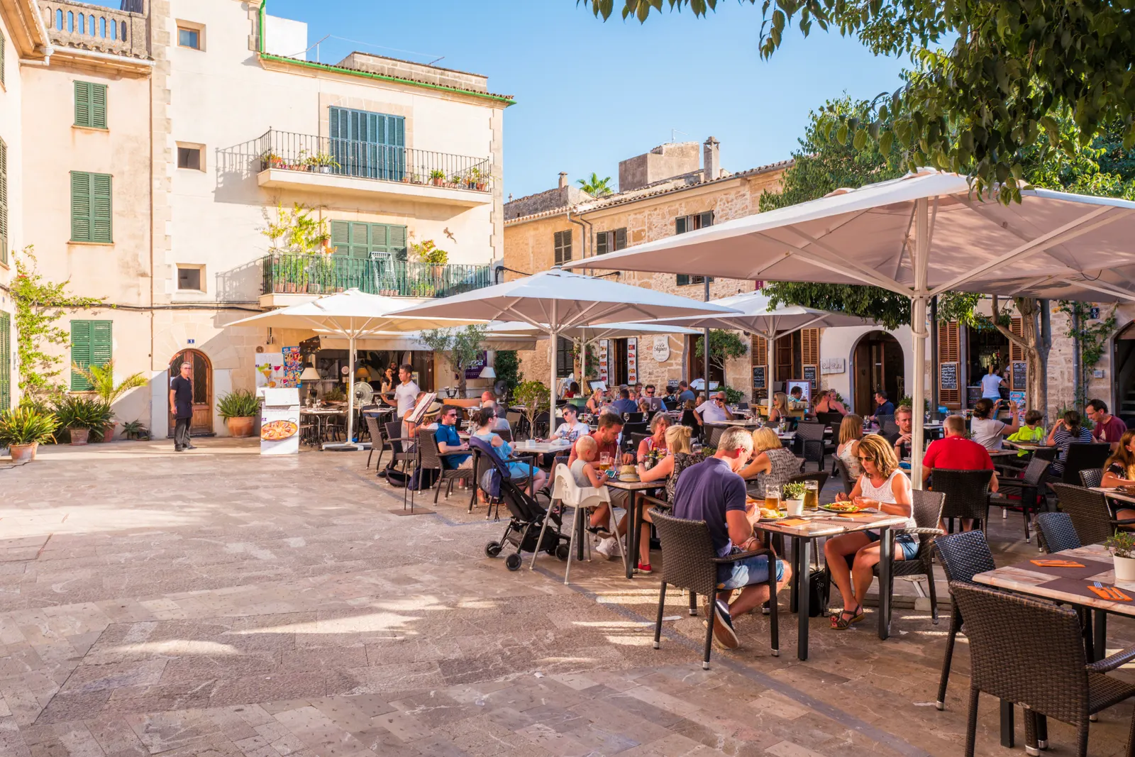 Una plaza del casco antiguo de Alcúdia, con las terrazas bajo las sombrillas y las fachadas de piedra