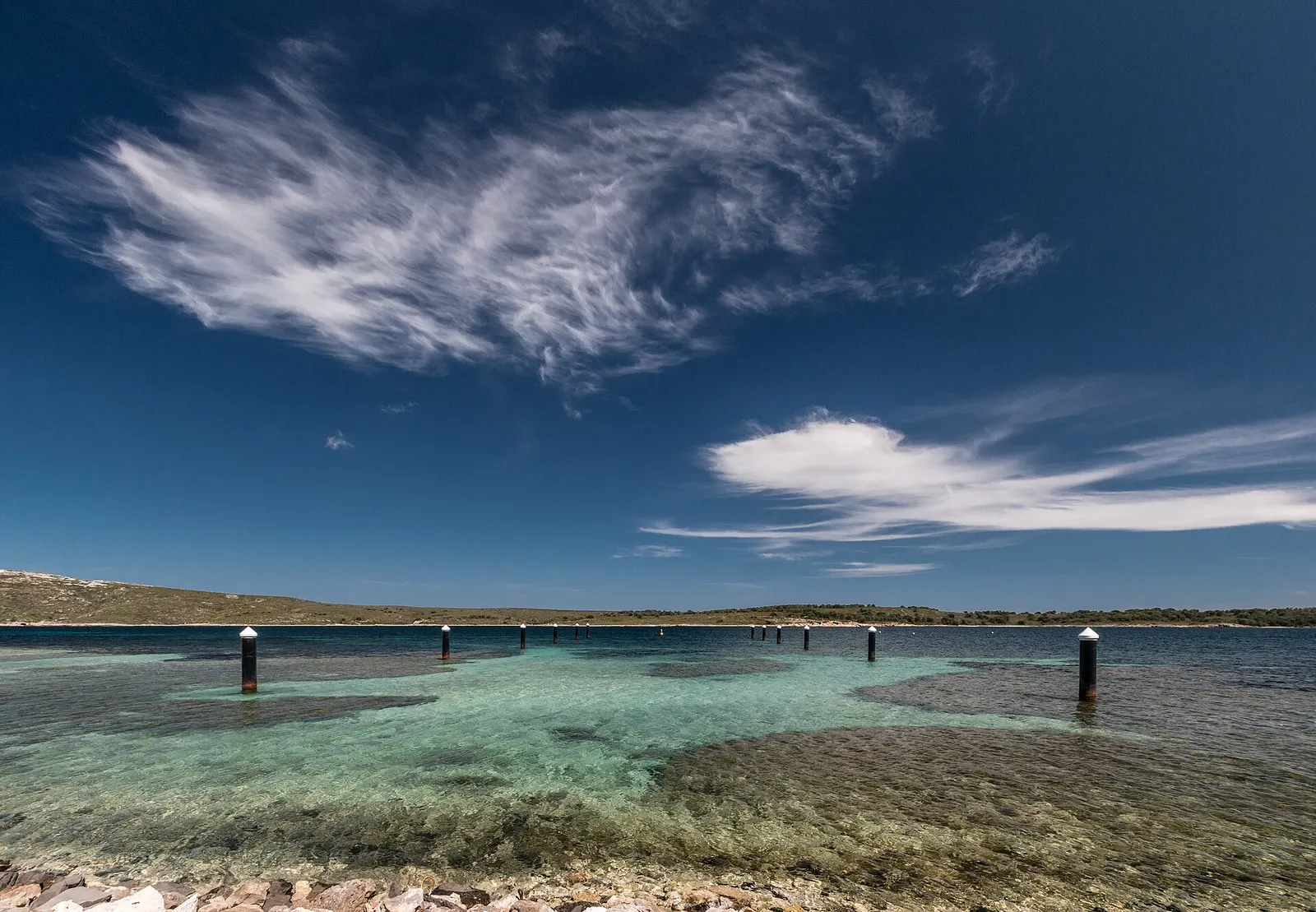 El agua clara de la bahía de Fornells con el pantalán de madera