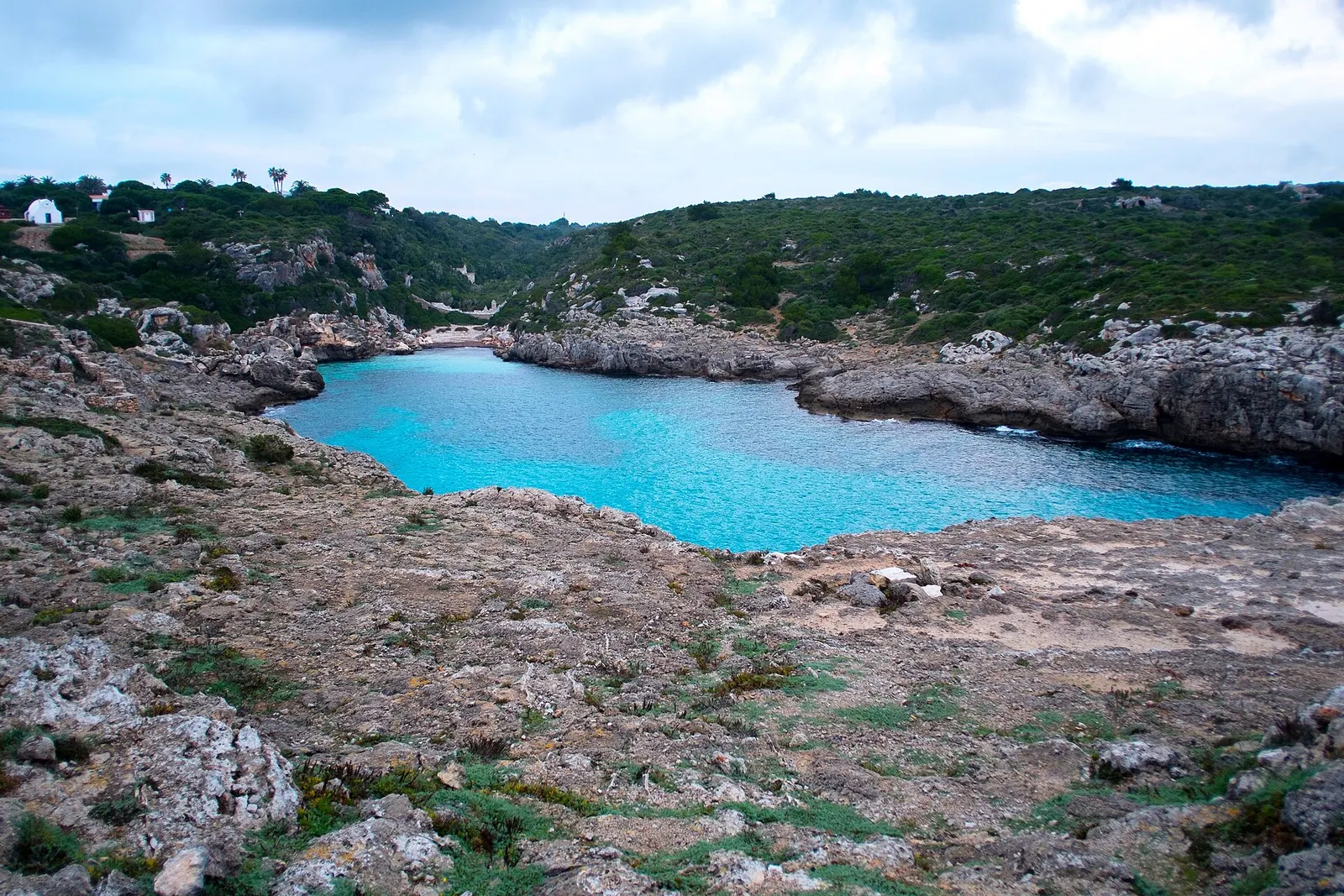 La cala de Binidalí encajada entre paredes de roca, con el agua de un azul intenso