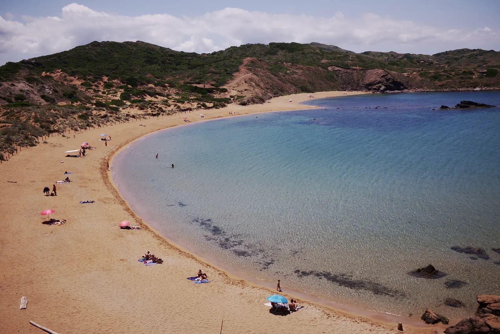 La playa de Cavalleria en media luna, con arena dorada y agua clara