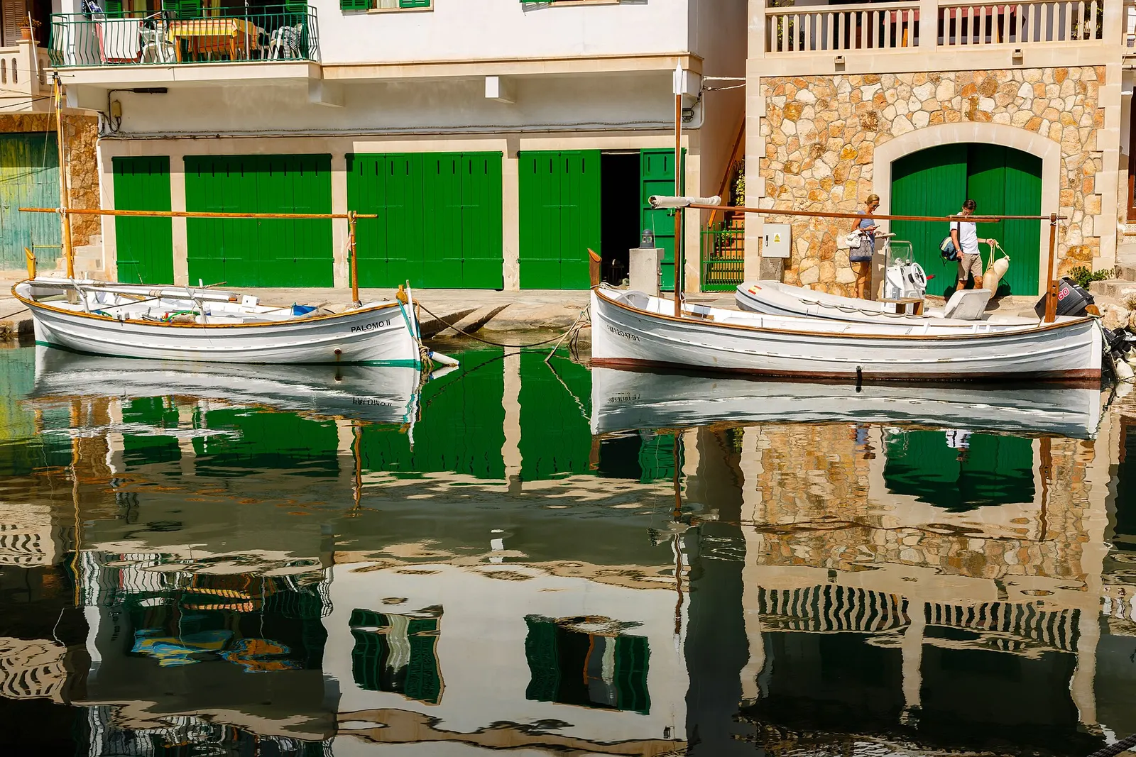 Las casetas de varada de Cala Figuera, con las puertas verdes y las barcas reflejadas en el agua
