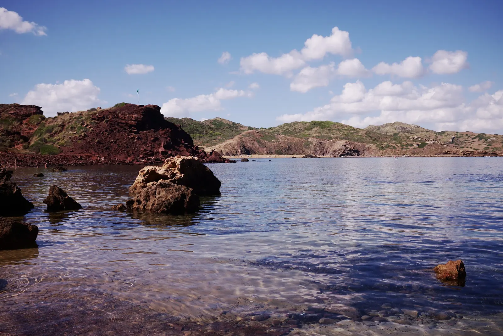 La roca rojiza del cap de Cavalleria cayendo sobre el agua, en la costa norte