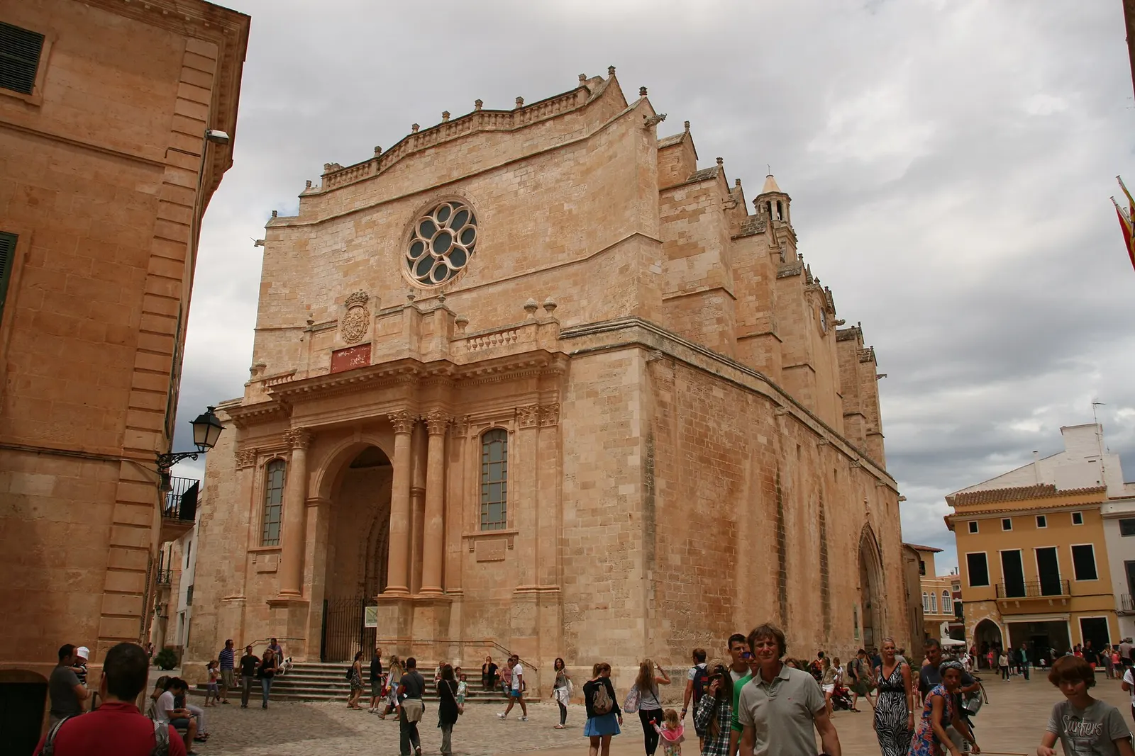 La fachada de la catedral de Ciutadella con su rosetón, y gente en la plaza