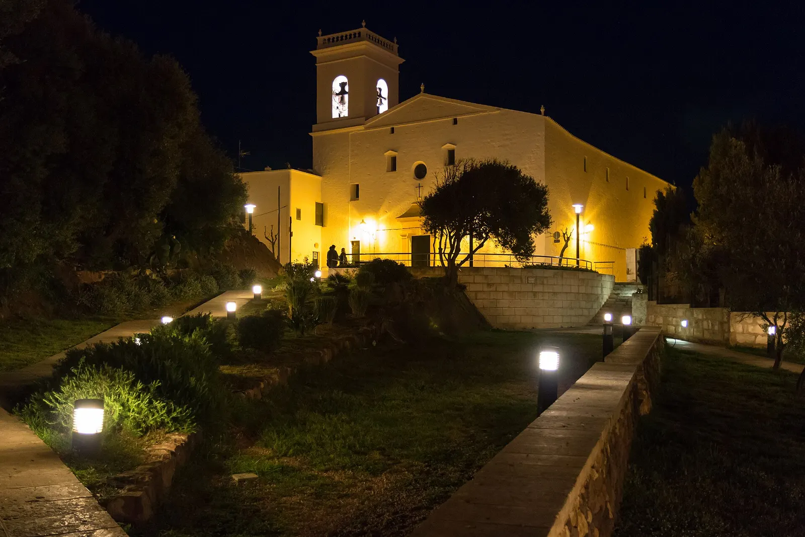 La iglesia de Es Mercadal iluminada al anochecer, sobre su terraza de piedra