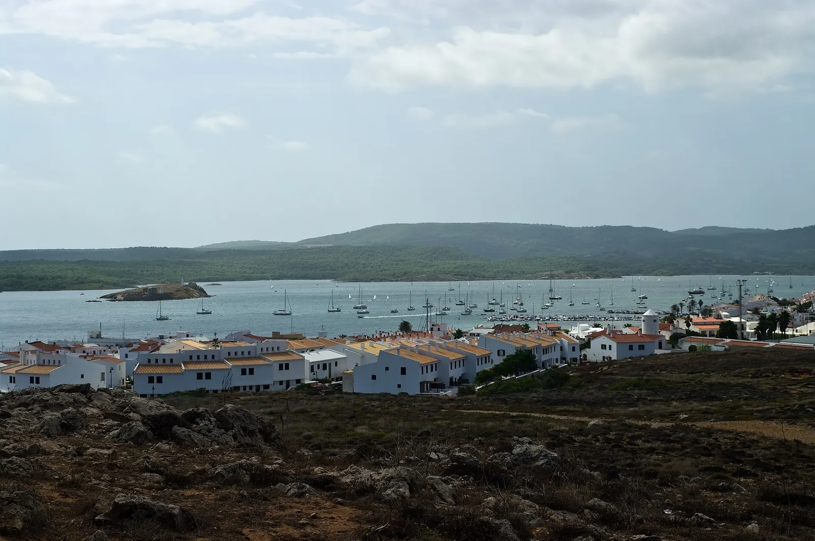 A baía de Fornells com os veleiros fundeados e a vila branca ao fundo
