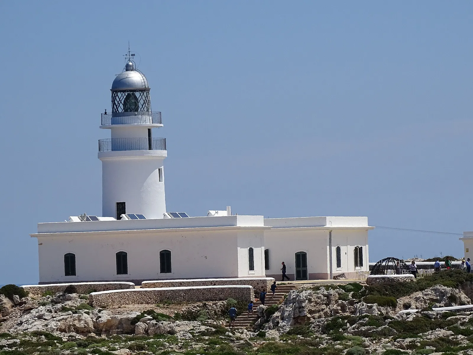 El faro blanco del cap de Cavalleria y las casas del farero, sobre la roca