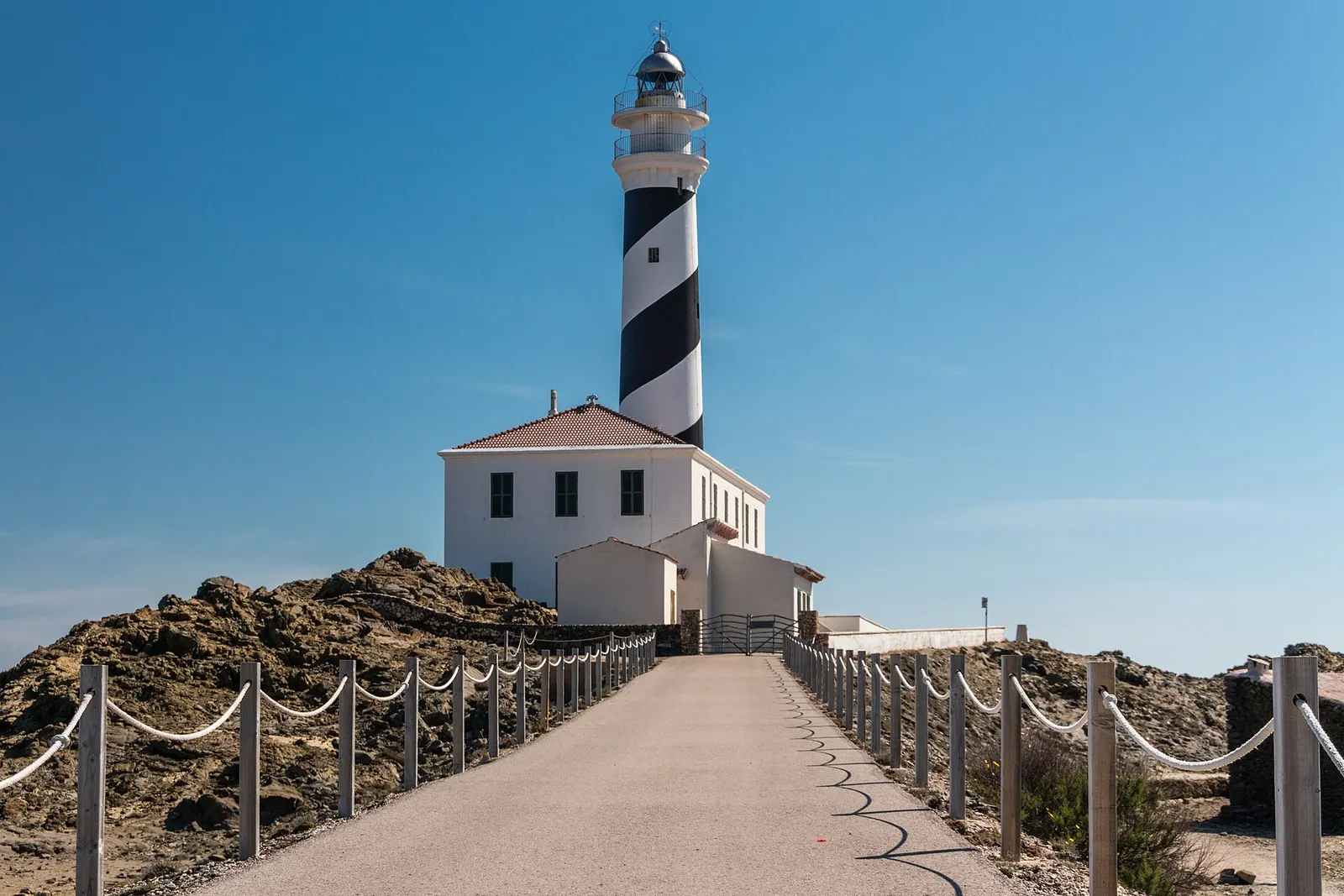 O farol de Favàritx, com a sua torre às faixas brancas e pretas ao fim do caminho