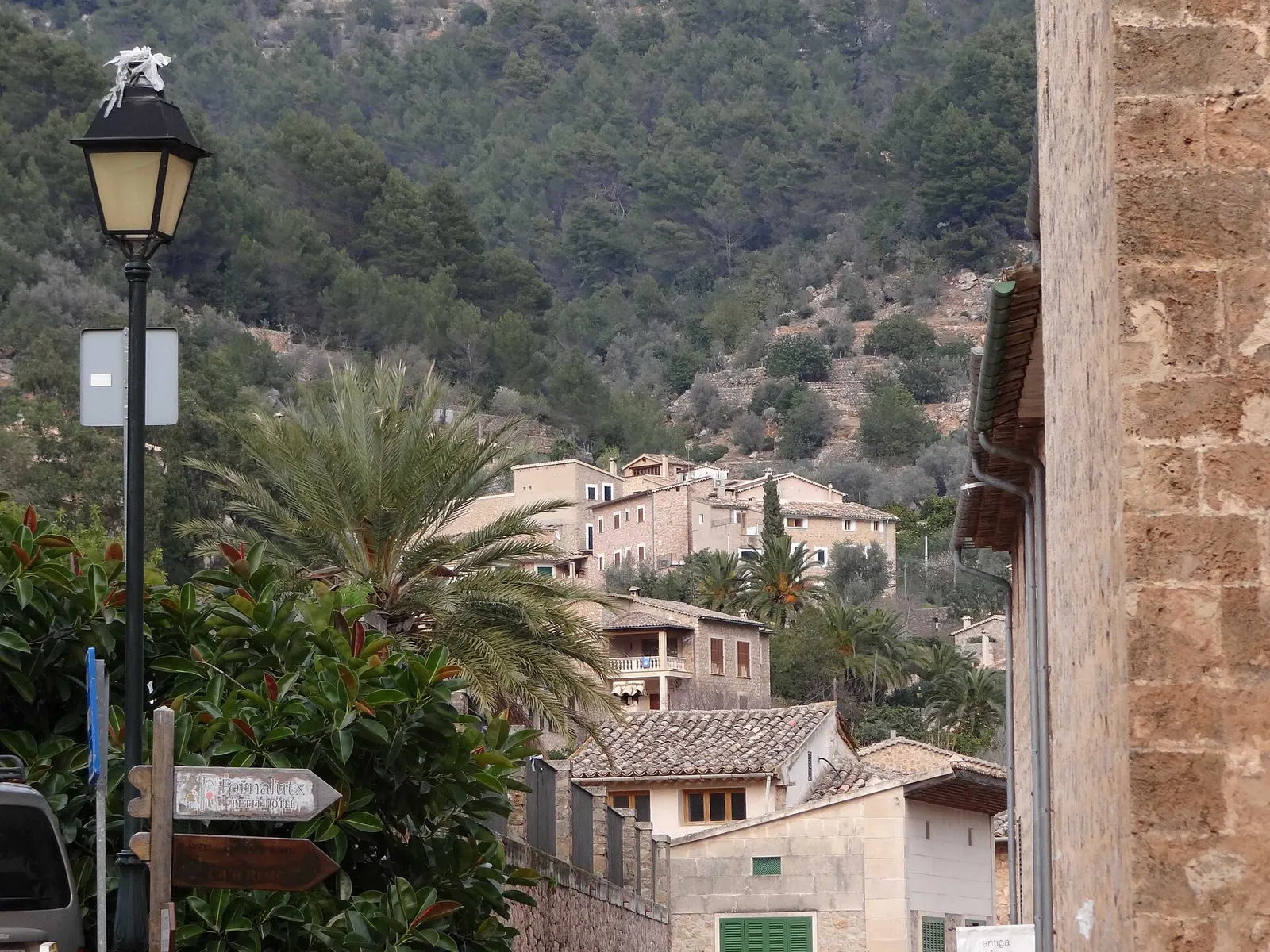 Las casas de Fornalutx escalonadas en la ladera, con una palmera y la montaña al fondo