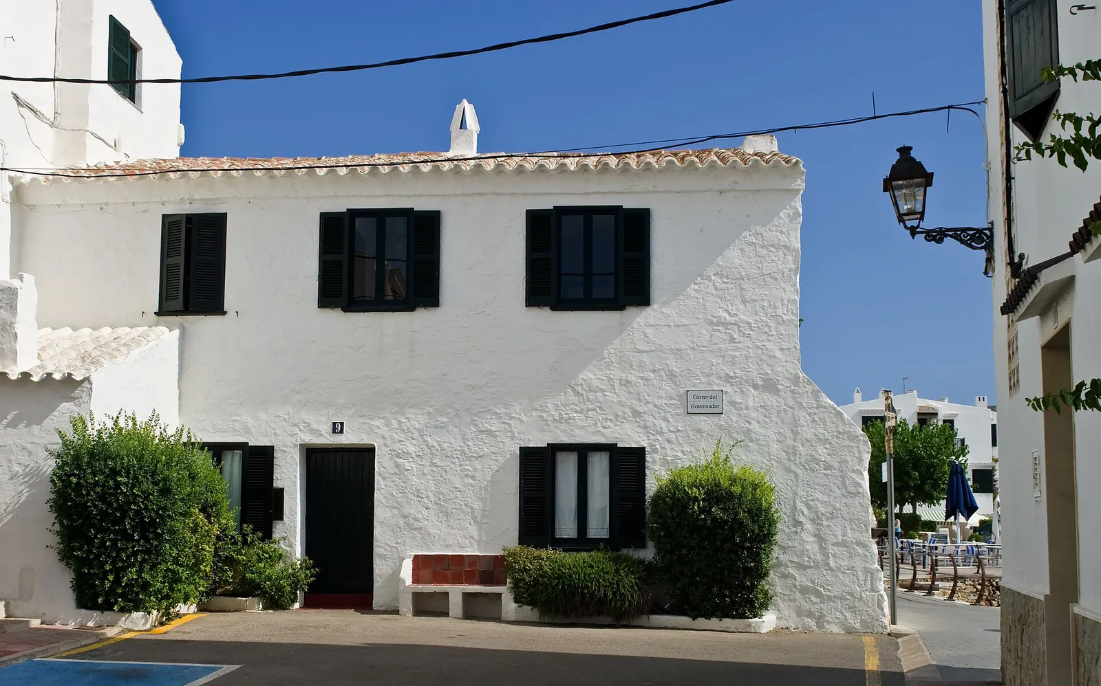 Uma rua de Fornells que desce até à água entre casas caiadas