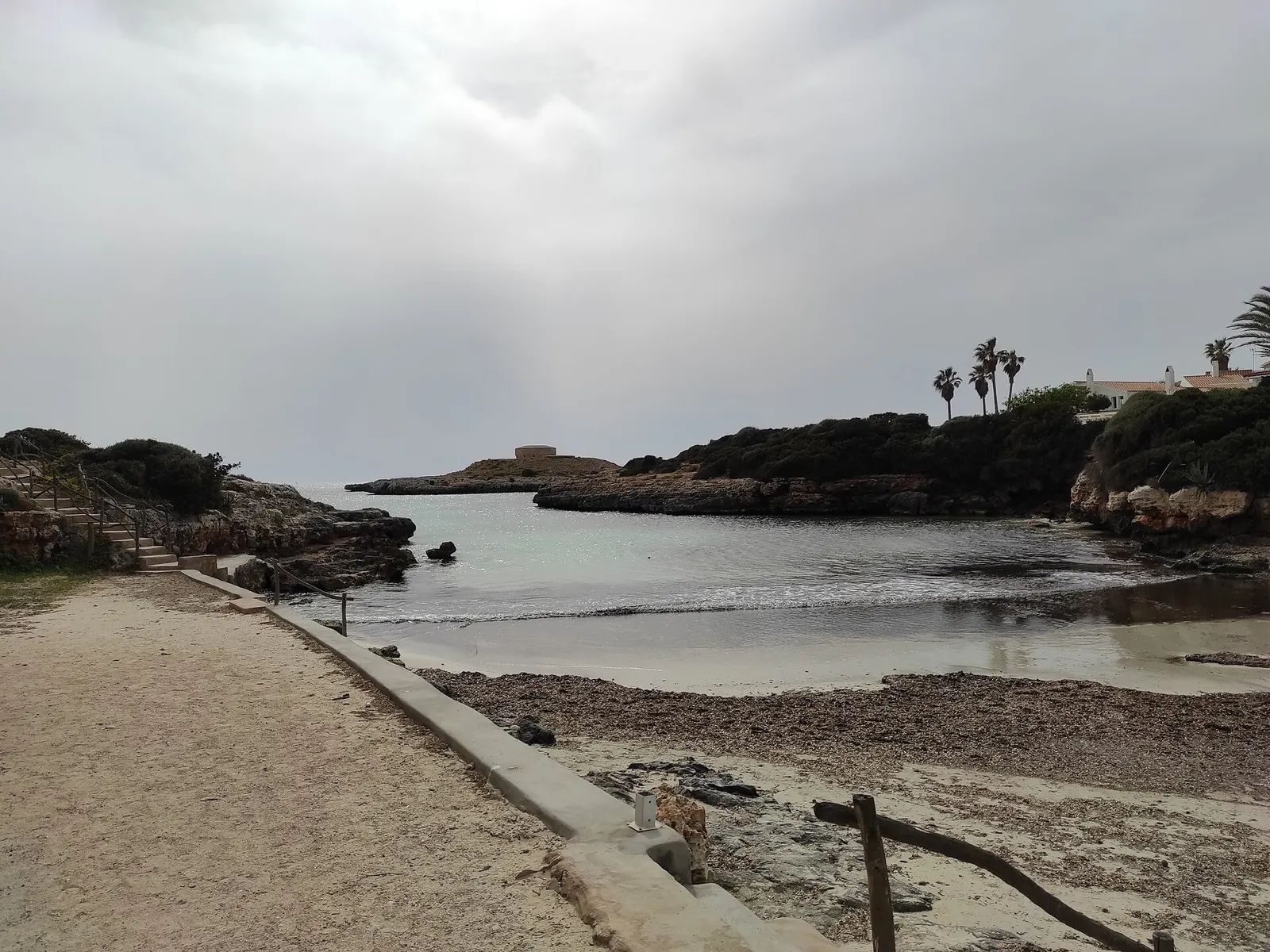 La orilla de Cala Blanca con la arena y el agua en calma