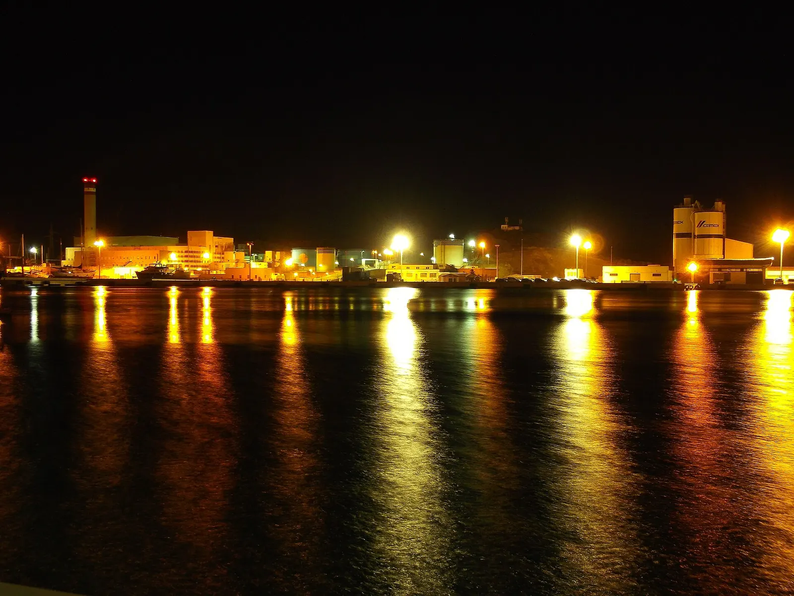 El puerto de Maó de noche, con las luces de la ribera reflejadas en el agua