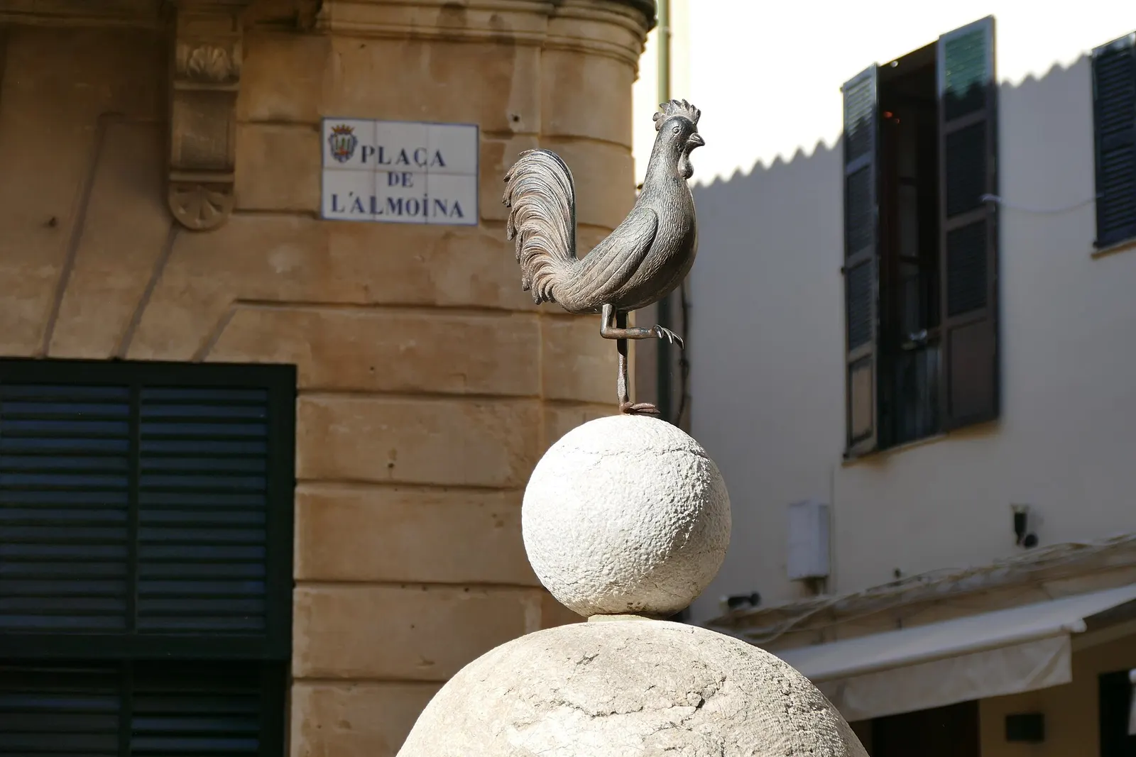 La placa de la plaça de l'Almoina de Pollença, sobre una fachada de piedra