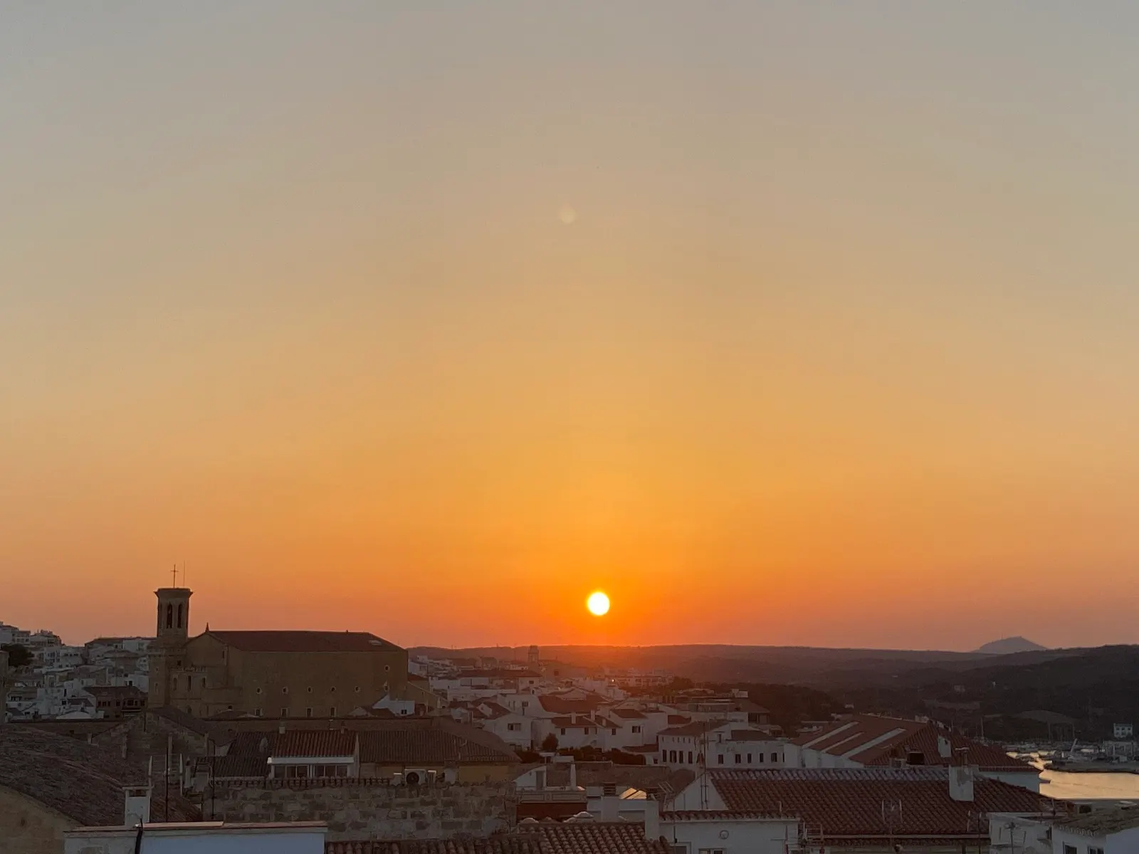 Pôr do sol alaranjado sobre as casas de Maó