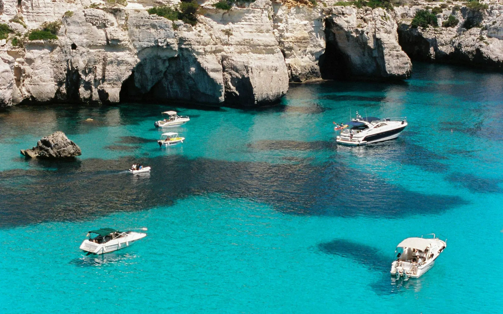 Litoral de acantilados y pinar de Menorca con el mar turquesa al fondo.