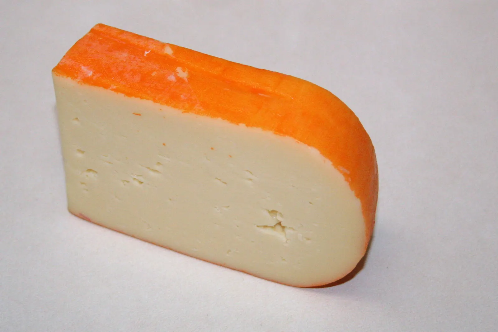 Una cuña de queso de Mahón-Menorca con su corteza anaranjada