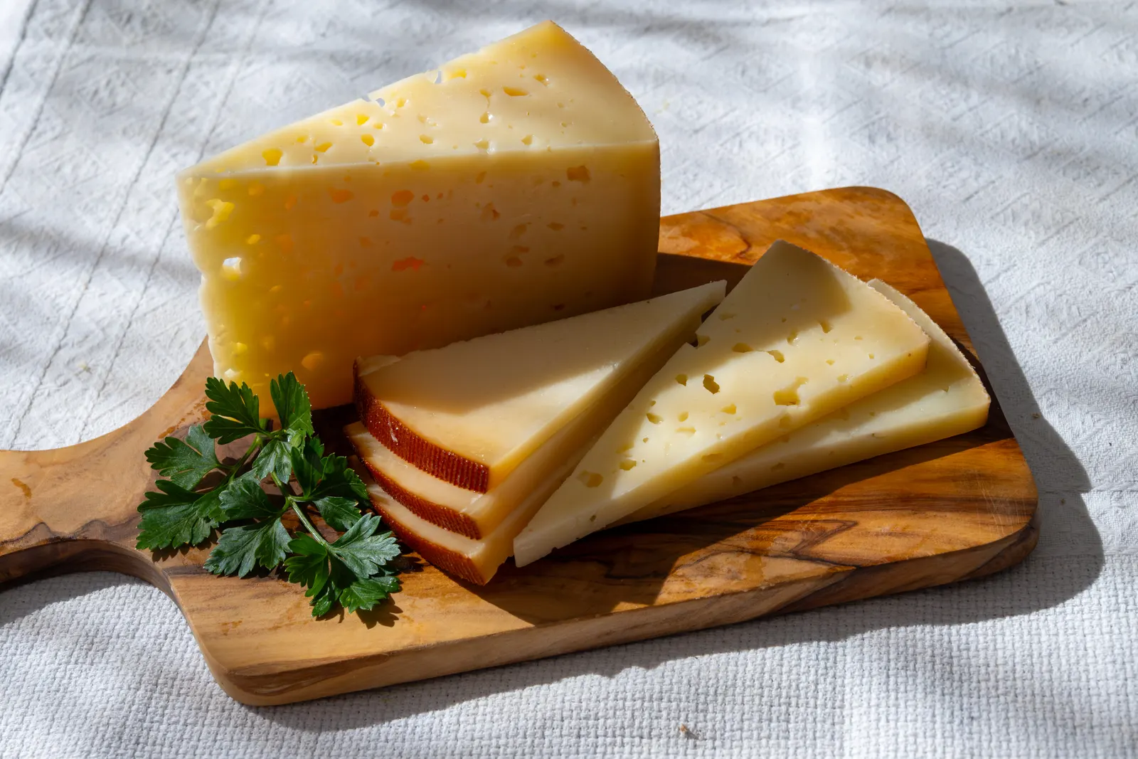 Cuñas de queso Mahón-Menorca de distintas curaciones sobre una tabla de madera.