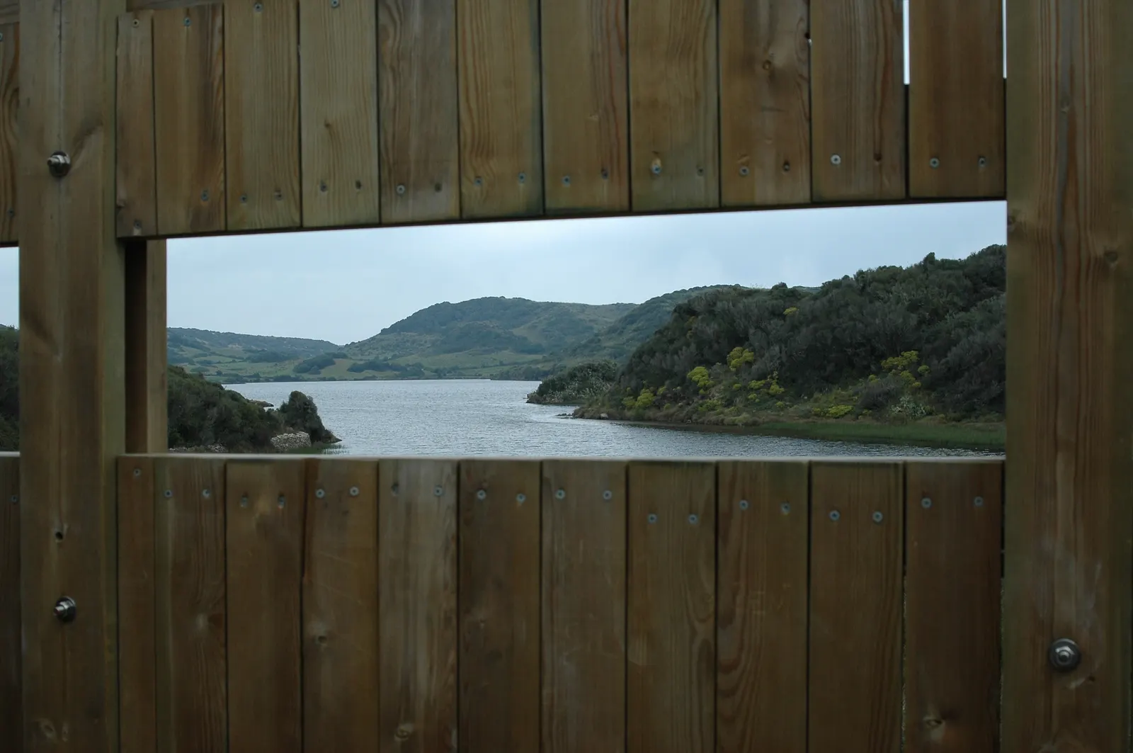 La vista sobre la laguna de s'Albufera des Grau, enmarcada por las tablas de madera de uno de los observatorios de aves del parque.