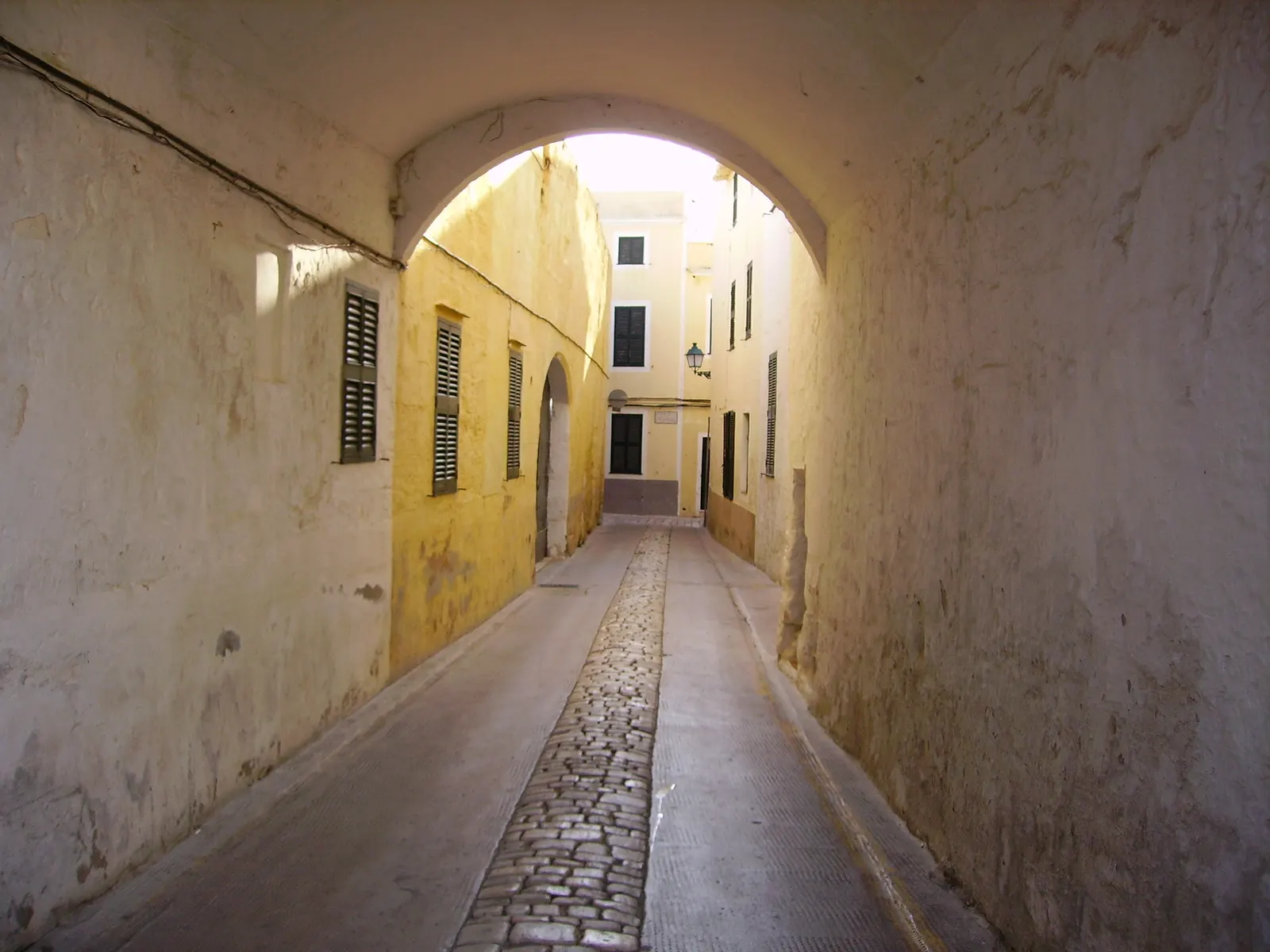 Una callejuela abovedada del casco antiguo de Ciutadella, con fachadas encaladas y en ocre.