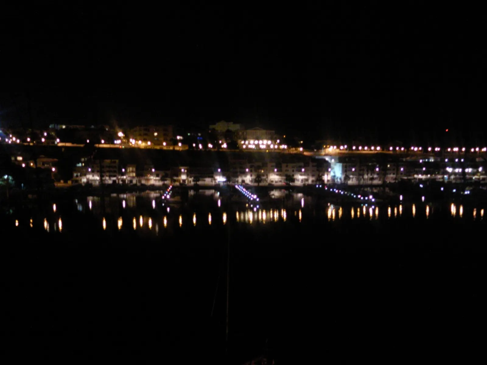 Il porto di Maó di notte, con le luci della riva riflesse nell’acqua calma