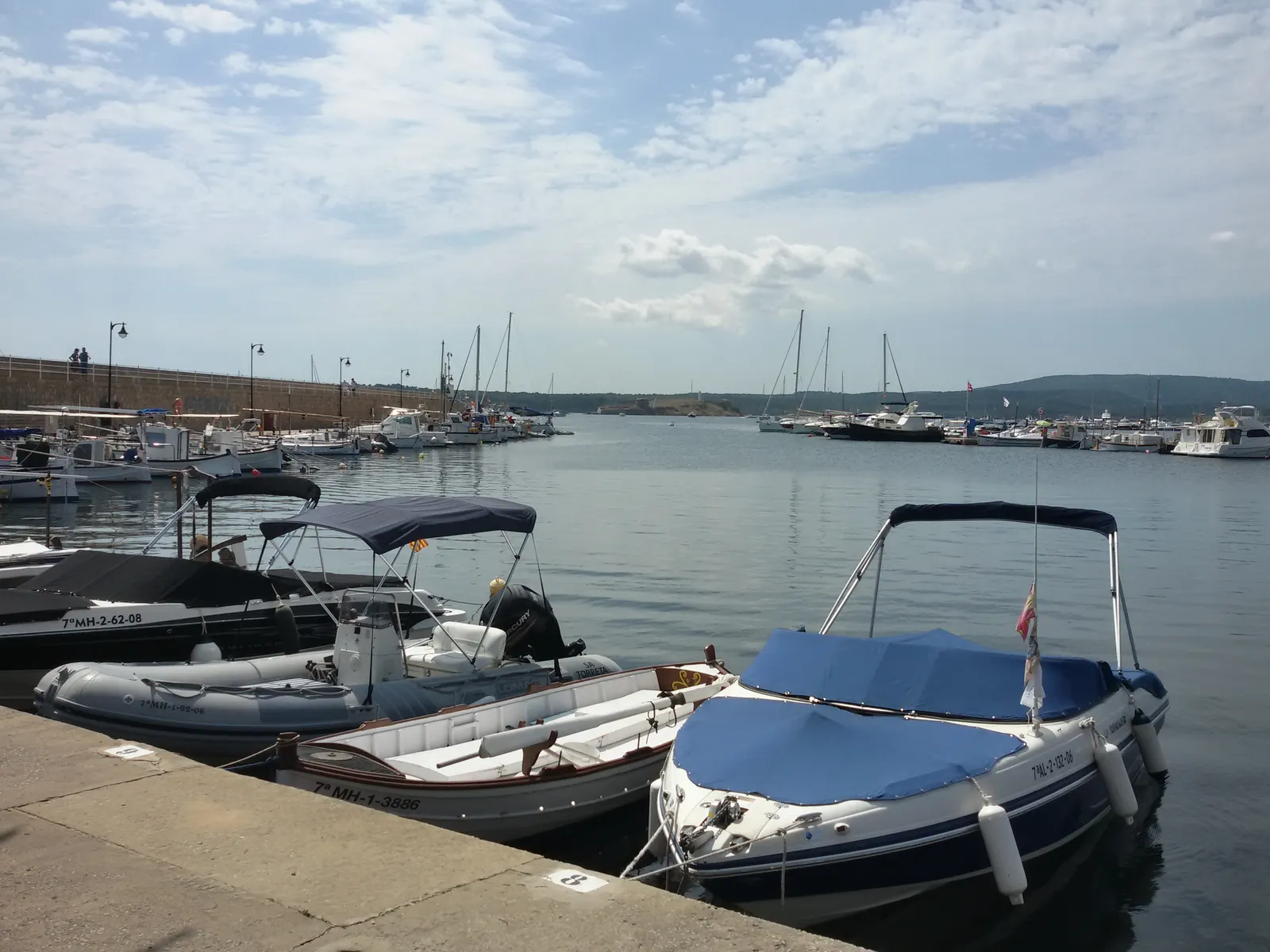 Barcas amarradas en el puerto de Fornells, con la marina al fondo.