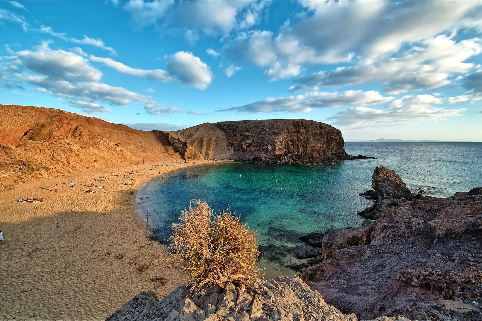 La playa de Papagayo casi vacía, una media luna de arena entre acantilados ocres y agua turquesa.