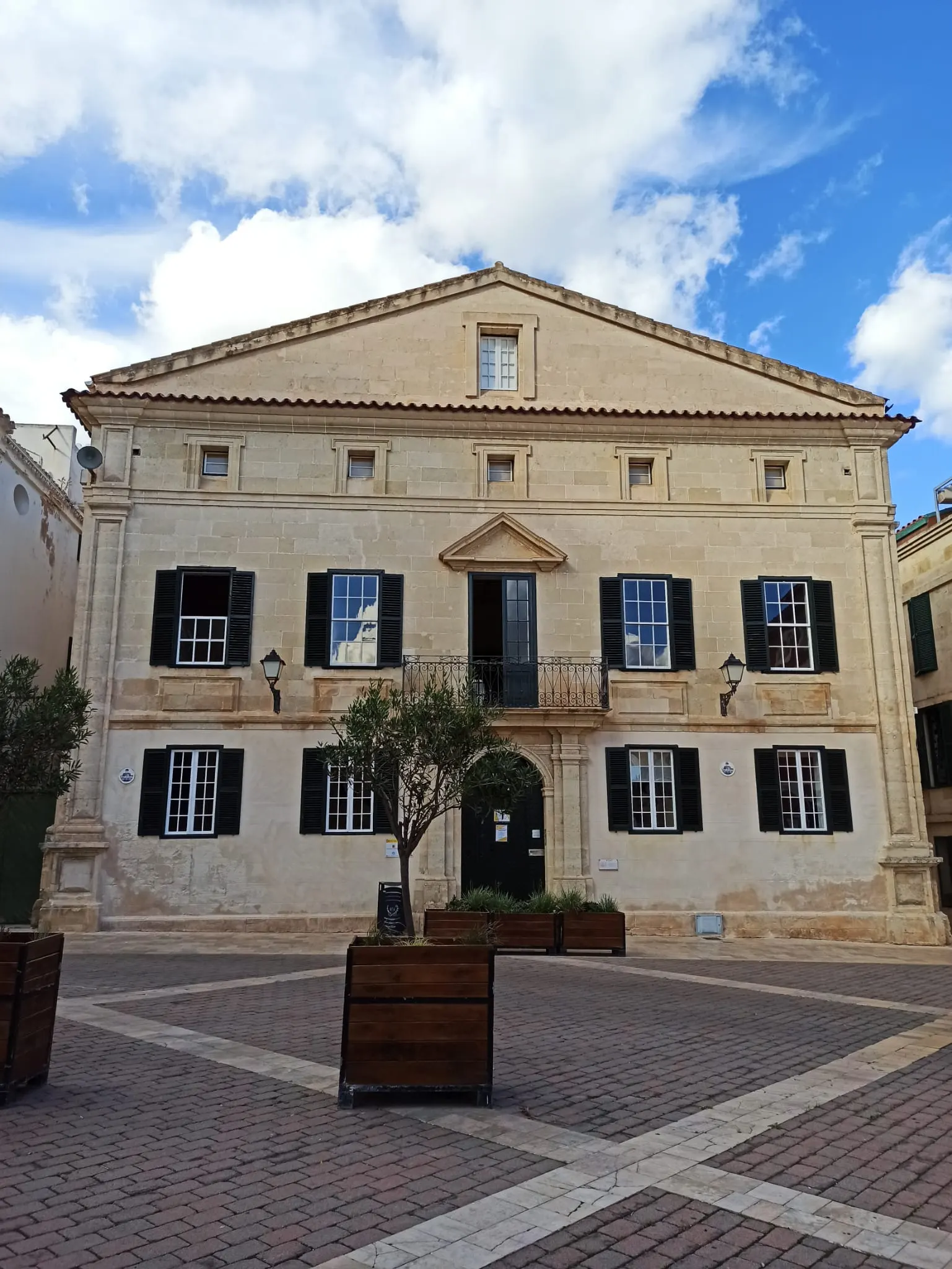 Un edificio de fachada blanca y contraventanas oscuras, de aire georgiano, en el centro de Maó.