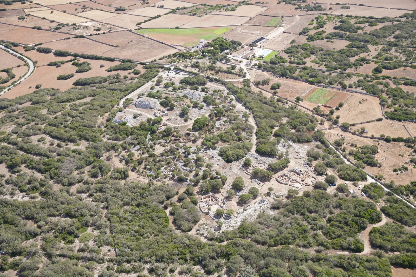 Vista aérea del poblado talayótico de Torre d'en Galmés, con sus círculos de piedra seca entre el monte bajo y los campos de cultivo de Alaior.