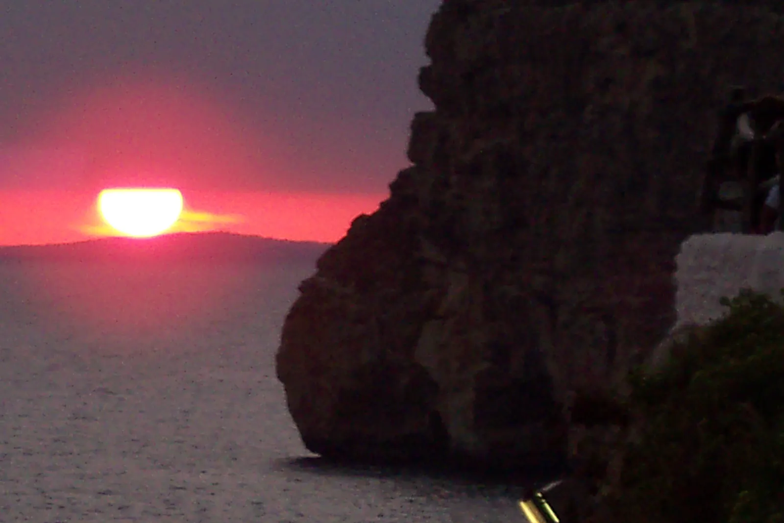 El sol se pone sobre el mar junto al acantilado de la Cova d'en Xoroi, con su terraza asomada al agua.
