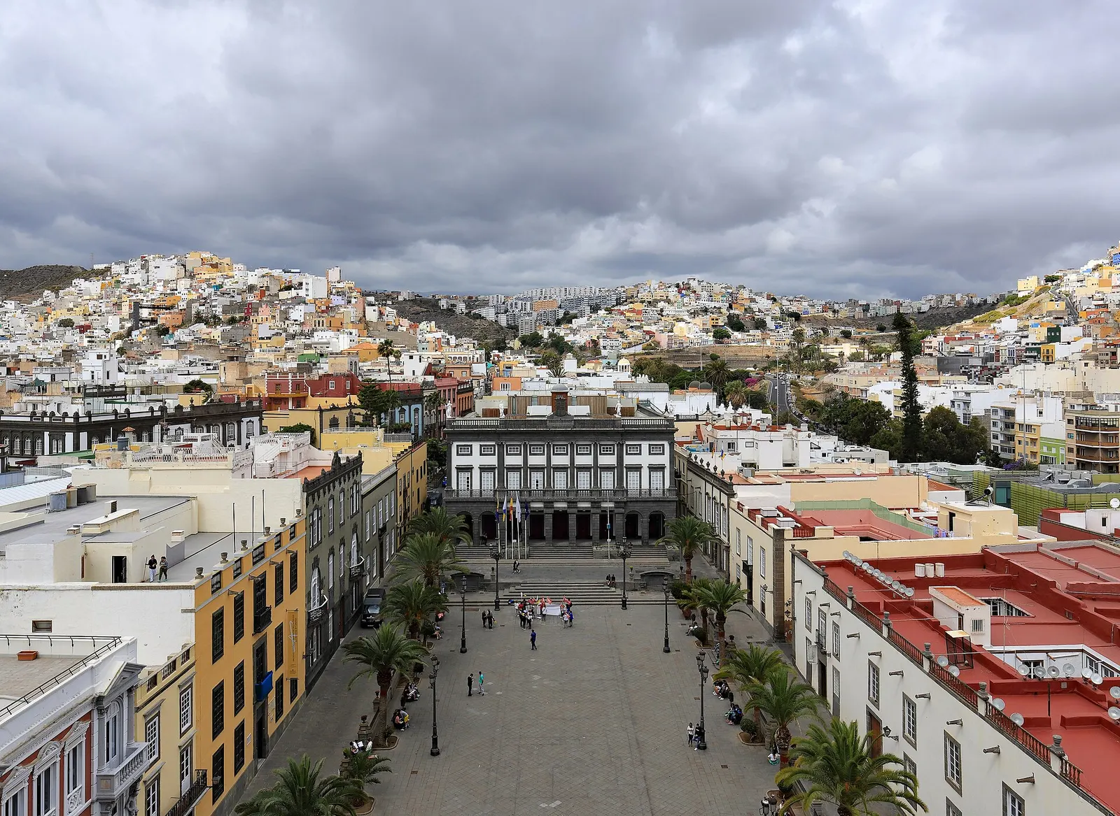 La plaza de Santa Ana con sus palmeras y el ayuntamiento, vista desde lo alto, con los barrios de Las Palmas subiendo por las lomas.