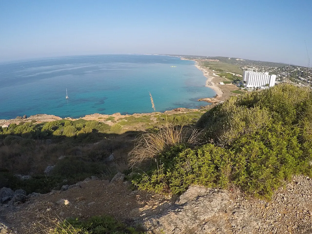 el gran arco de la playa de Son Bou, la más larga de Menorca, vista desde el acantilado